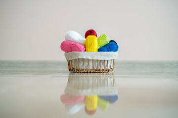 some different colorful yarn rolls in the basket on shelf or table at home, homemady hobby