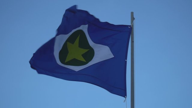 Beautiful flag of Mato Grosso state waving in the wind on sunny summer day with blue sky. Concept of state, symbol, republic, Brazil, cultural identity, democracy, geography and politics.