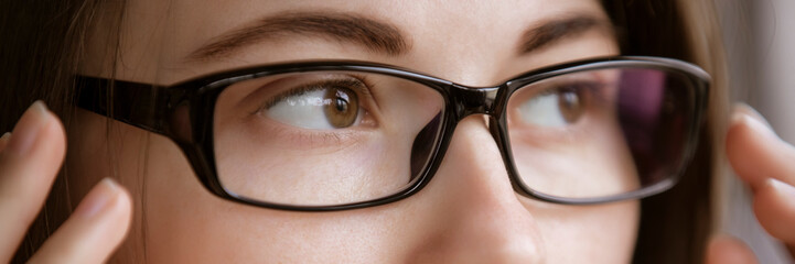 Myopia or hyperopia, woman looking through optical eyeglasses, wide banner