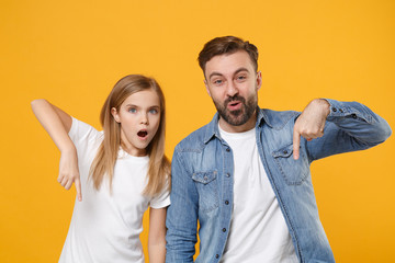 Fototapeta premium Shocked bearded man in casual clothes have fun with child baby girl. Father little kid daughter isolated on yellow background. Love family day parenthood childhood concept. Point index fingers down.
