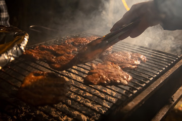 in the evening a barbecue grill on which tasty juicy steaks are grilled over an open fire, a hand...