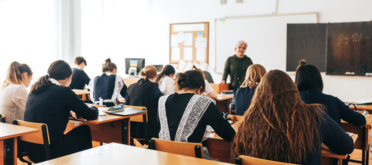 a classroom, a lecture, a lesson is going on, students are listening to the teacher, the teacher...