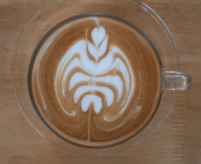 Top view of hot coffee latte cup with beautiful art shape on the table
