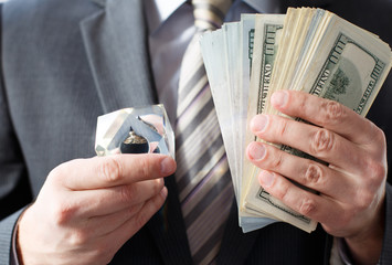 Businessman in suit, tie holds in hands drop of black oil of Brent brand in crystal cube.Pack of...