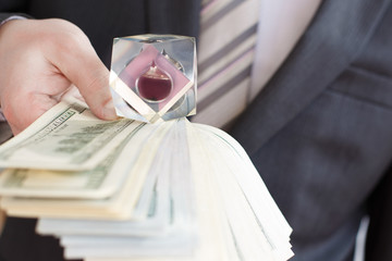 Businessman in suit, tie holds in hands drop of black oil of Brent brand in crystal cube.Pack of...