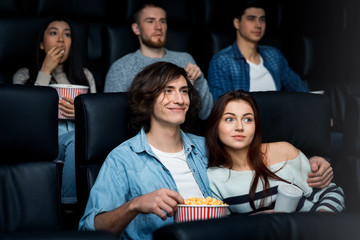 Hugging in the cinema. Lovely young couple enjoying their date in movie theatre