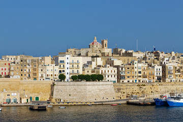 Fototapeta na wymiar Valletta City overlooking the Dock 1 Area of the Grand harbour with its traditional Stone built High Rise Apartments overlooking the Quay.