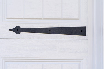 Black powder coated steel spade strap hinge pointing to left on a raised panel white garage door on...