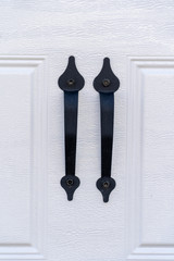 Elegant black powder coated spade lift handle pair on a raised panel white garage door
