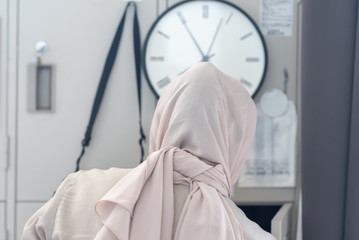 Asian Muslim Girl Pastel cream hijab Wearing a long-sleeved shirt in cream color Prepare to go out for personal business Standing front of a light gray locker. Concept of a business Muslim girl
