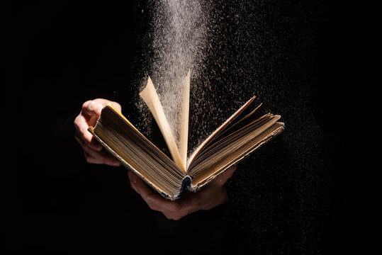 cropped view of woman holding holy bible with dust on black background