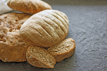 Delicious homemade bread. Loafs of whole grain bread of different shapes on a dark background. Background with bread, top view, copy space