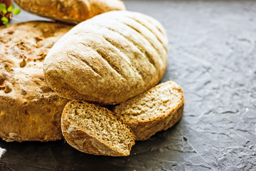 Assorted homemade bread close-up. Several loaves of bread on a dark table. The concept of home baking and bread production. Background about bread
