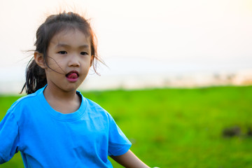 Asian girl kindergarten children wear blue shirts, standing, playing at the water's edge when the sun is about to set.
