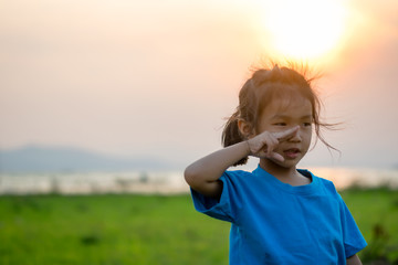 Asian girl kindergarten children wear blue shirts, standing, playing at the water's edge when the sun is about to set.