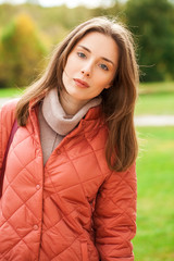 Close up portrait of a young beautiful brunette girl in coral coat