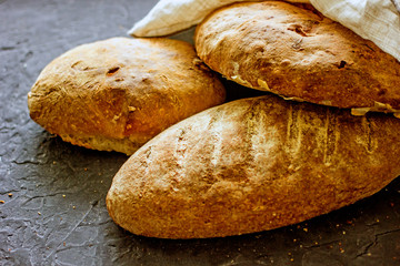  Whole grain bread. Fresh homemade bread. French sourdough bread. Loaves of various bread on a dark background, top view, copy space