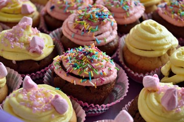 Colorful cupcakes decorated with spring and Easter candy sprinkles. Other cupcakes blurred in the...