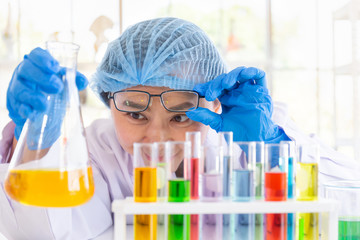 Discovering a cure for an Asian female scientist who is concentrated, holding a test tube and watching while working.