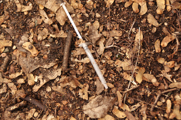 thin syringe addict lies on the ground in dry foliage, addiction concept