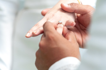 On the wedding day, the bride wears a diamond wedding ring for the groome. The bride's ring finger...