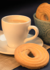 Coffee with butter cookies on dark background