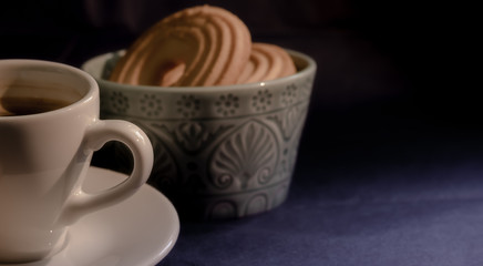 Coffee with butter cookies on dark background
