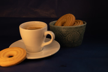 Coffee with butter cookies on dark background