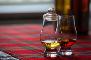 Special tulip-shaped glass for tasting of Scotch whisky on distillery in Scotland, UK and red tartan