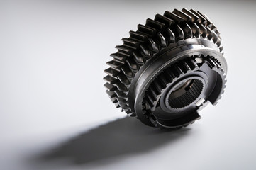 New parts on a gray background. Gears of gear shifting torque transmission. Conceptually mechanical background. Shiny gear box gear teeth