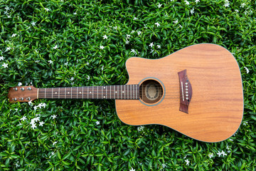 Acoustic guitar lays on grass field background