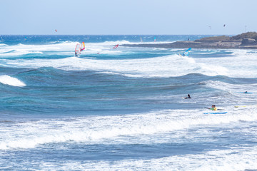 Surfers and windsurfers on the waves of El Medano
