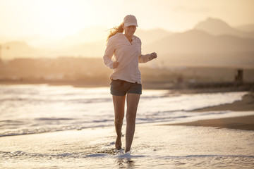 Fototapeta na wymiar Young woman running on the La Tejita beach