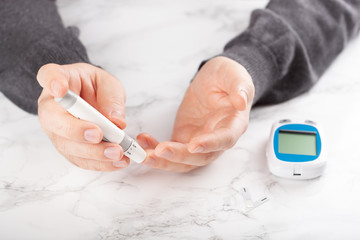 man hands using lancet on finger to check blood sugar or ketones level by glucose meter. medicine...