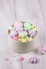 Colored Meringue Cookies in a white box, on a light wooden background.