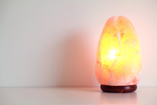 Pink salt lamp standing on the table with warm light on