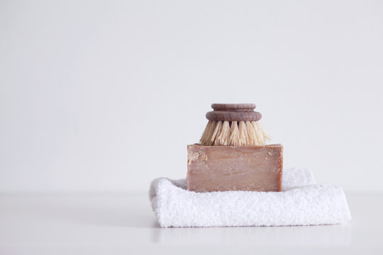 Wooden dishwashing brush and a piece of soap bar on a white towel on a table in a zero waste household