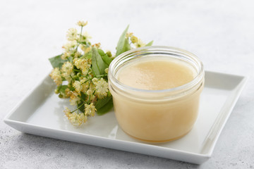 Obraz na płótnie Canvas Honey jar with linden blossoms close up