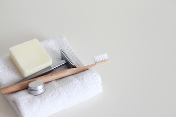 Bamboo toothbrush, safety razor and soap bar on the white towel in a bathroom