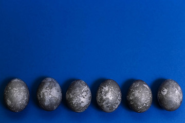 Eggs with marble stone effect painted with natural dye carcade flower on blue sparkling background