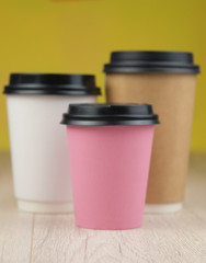 Many color disposable paper cups with lids on colorful paper background