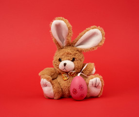 cute brown bunny and pink colored eggs on a red background