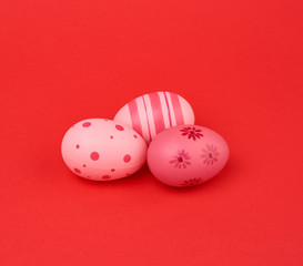 three colored pink easter eggs on a red background