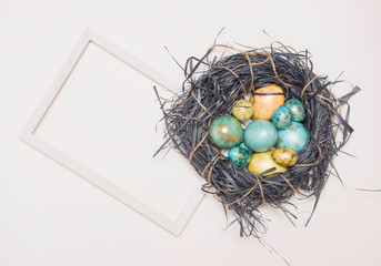 Easter eggs in a nest and a white text frame. On a white background. Golden colors , happy Easter. Top view, flatlay.