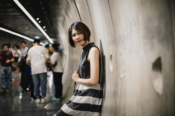 Portrait of Asian young short hair beautiful woman wearing glasses and grey dress in tunnel