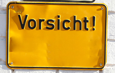 Gelbes Schild mit Aufschrift Vorsicht einer Hauswand,  Deutschland, Europa