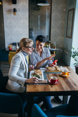 Fototapeta na wymiar women friends eating in restaurant, using mobile phone