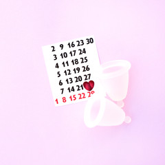 Menstrual cups with a calendar on a pink background.
