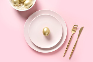 Easter table setting with golden eggs in bowl on pink. Elegance dinner. Top view.