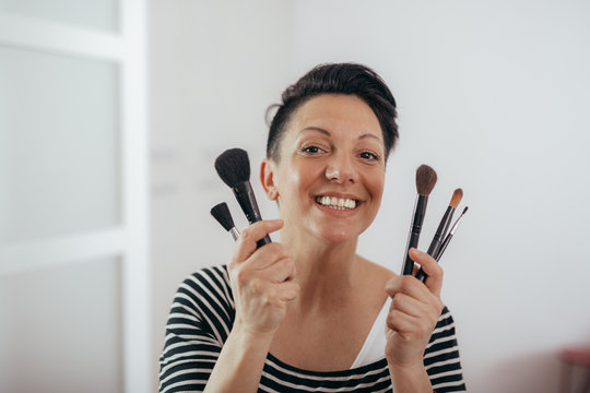 mid aged woman holding makeup brushes